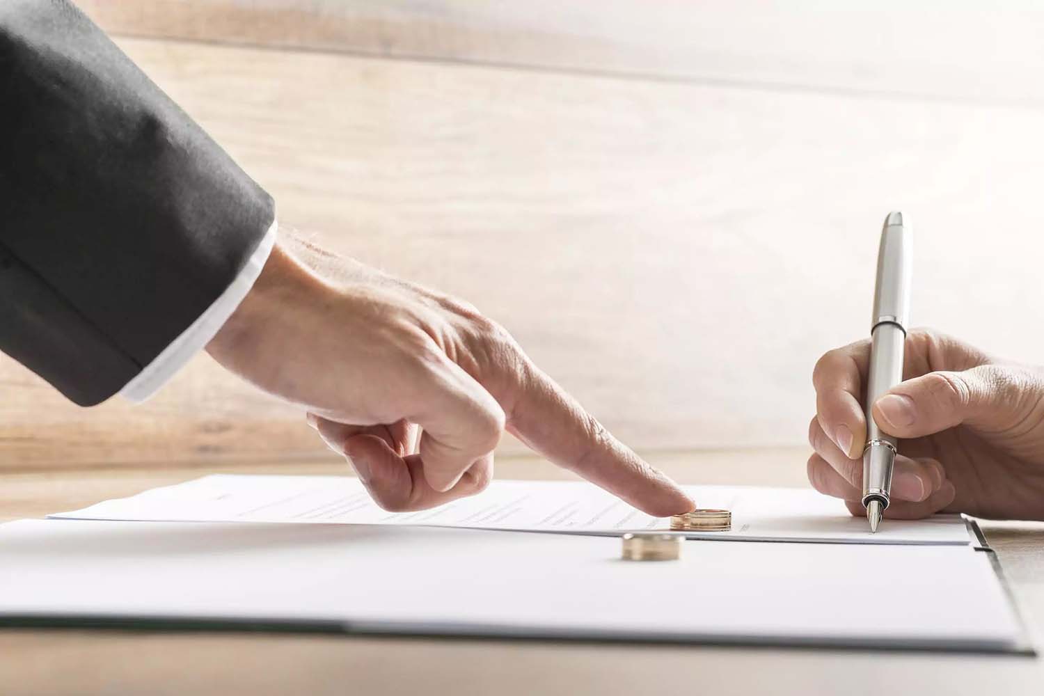 Cliente firmando contrato prenuncial con abogado. Se ve el contrato y los anillos matrimoniales